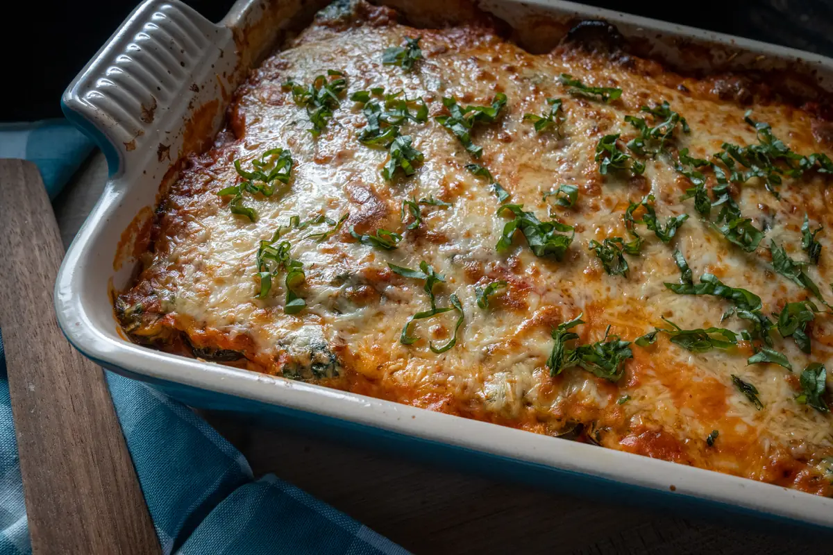 Polenta lasagna in a blue baking dish, topped with browned cheese and parsley.