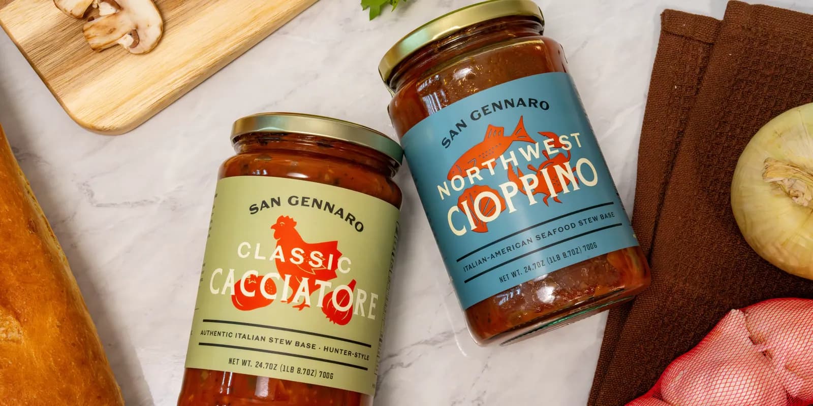 A jar of Classic Cacciatore and a jar of Northwest Cioppino side by side on a marble counter.