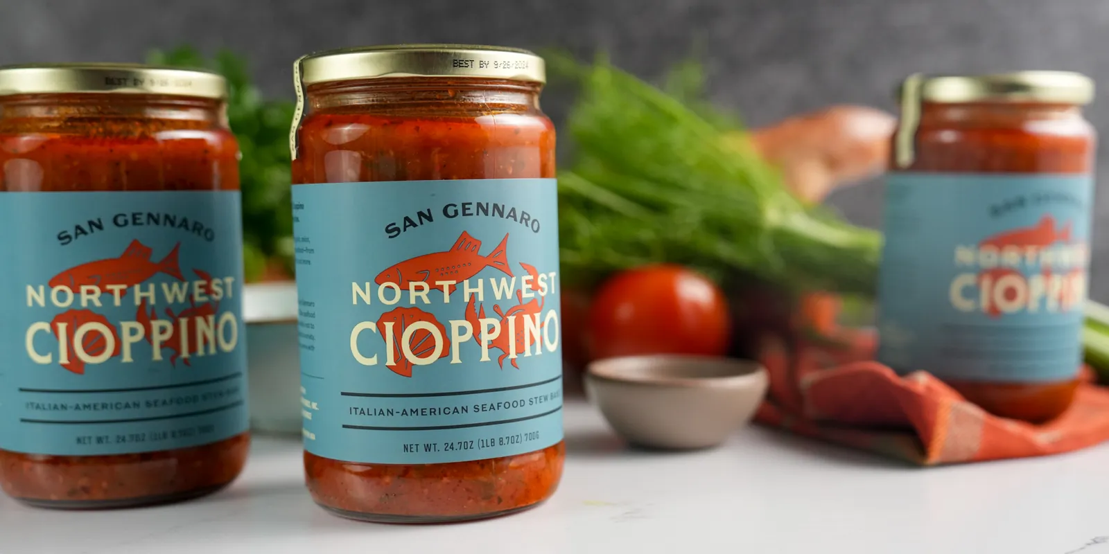 Three jars of San Gennaro Northwest Cioppino stew base on a marble counter.