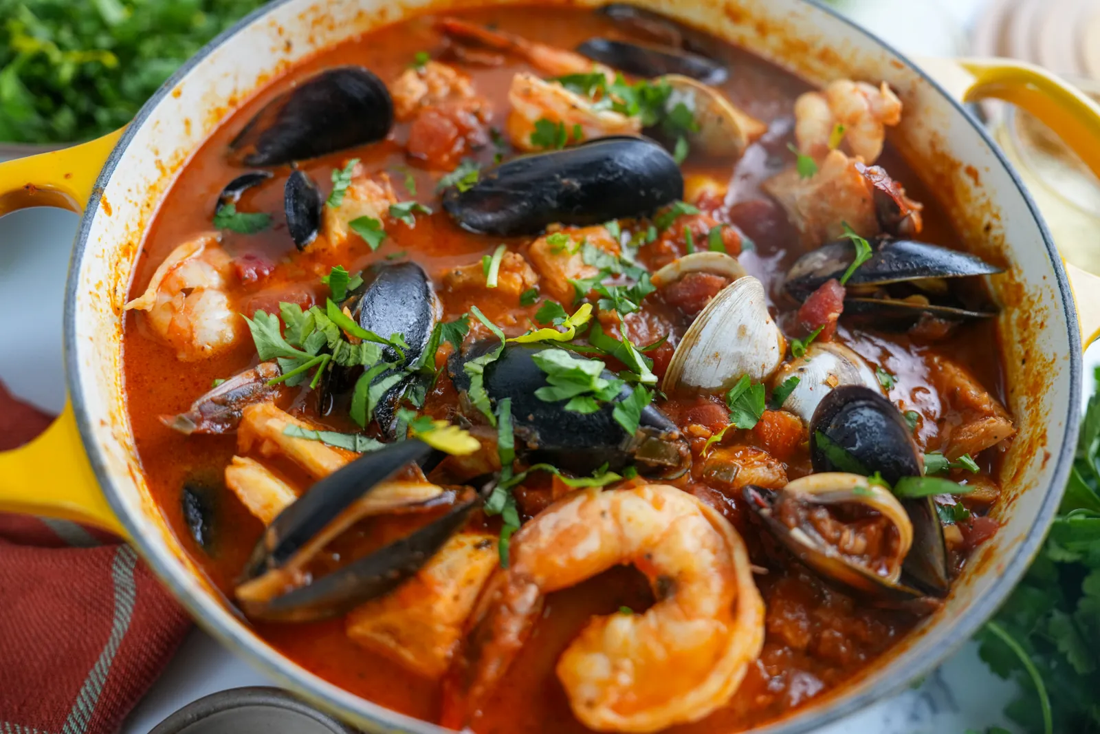 A pot of cioppino with mussels, clams, shrimp and fish in tomato broth.