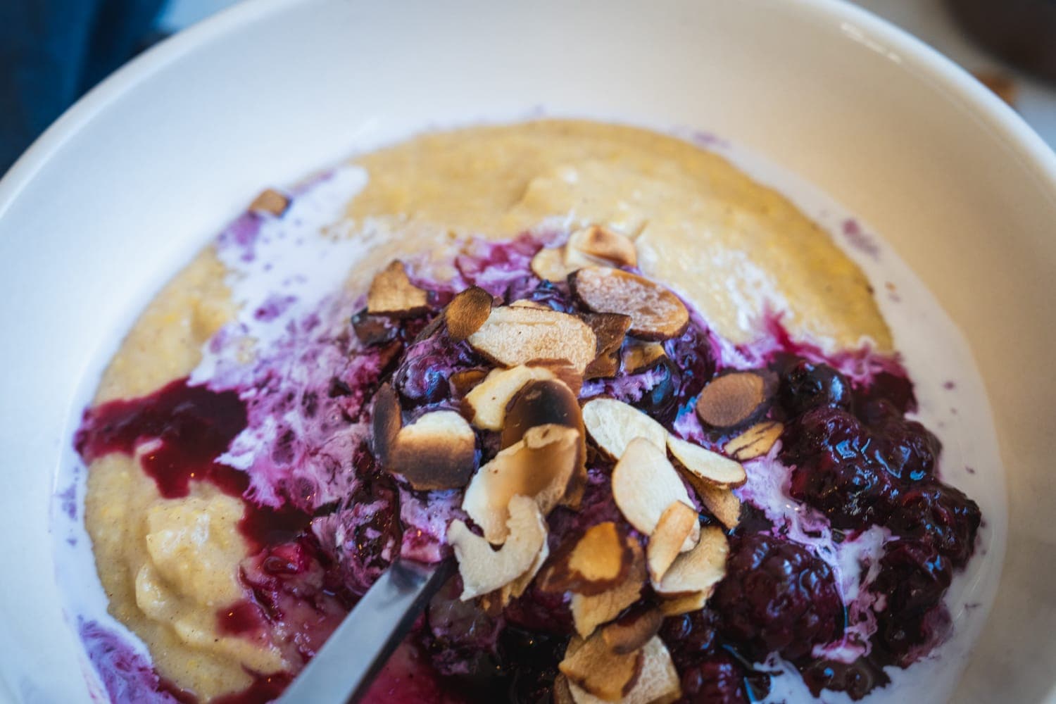 A bowl of warm polenta porridge topped with berries and maple syrup.